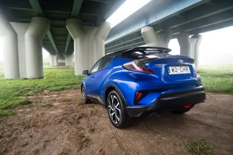 Niebieski Toyota C-HR 2018 zaparkowany pod mostem.