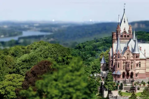 Schloss Drachenburg thront majestätisch inmitten üppiger Wälder, mit Türmchen und Zinnen, die in den Himmel ragen.