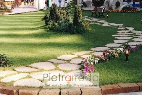 Un sentiero sinuoso di pietre irregolari attraversa un prato verde, creando un passaggio suggestivo nel giardino.