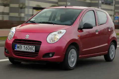 Czerwony Suzuki Alto z polskimi tablicami rejestracyjnymi WB 1606C jedzie po drodze.