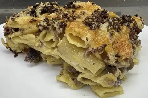 Un invitante piatto di pasta al forno, la ricetta della nonna, con pasta rigata, ragù e formaggio filante.