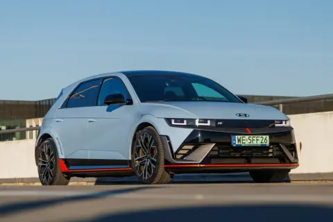 Sportowy Hyundai Ioniq 5 N z czerwonymi akcentami i czarnymi felgami na tle betonowego muru i błękitnego nieba.