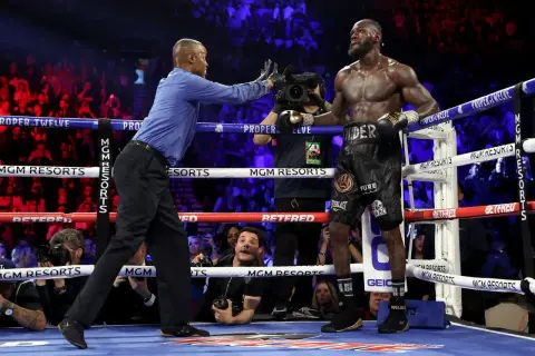 Referee stops the fight, signaling the end. Deontay Wilder stands, exhausted but victorious, as the crowd roars.