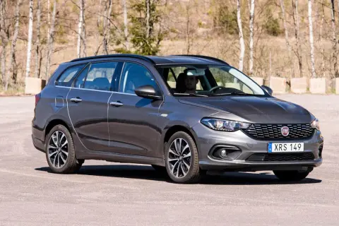 En mörkgrå Fiat Tipo kombi står parkerad utomhus. Bilen har en man bakom ratten.