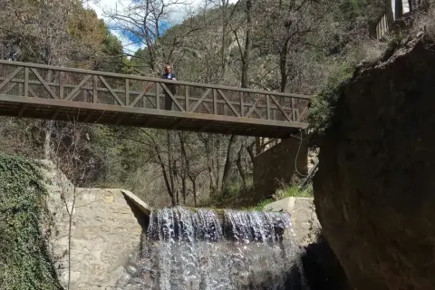 Puente metálico sobre cascada en la fabriquilla laujar. Una persona observa el agua.
