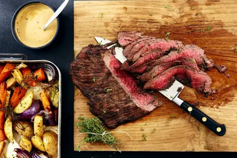 Saftig flankstek i ugn, skivad och serverad med ugnsrostade rotfrukter och en krämig sås.