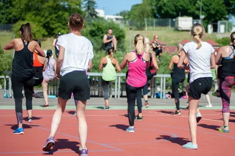 Grupa kobiet ćwiczy na świeżym powietrzu. Zastanawiasz się, ile kcal to kilogram? Ta aktywność spala kalorie, pomagając osiągnąć cel.