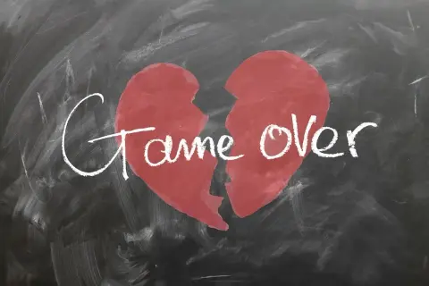 Ein zerbrochenes Herz auf einer Tafel mit der Aufschrift "Game Over". Ein Symbol für den tiefen Schmerz und die Trauer nach einer Trennung.