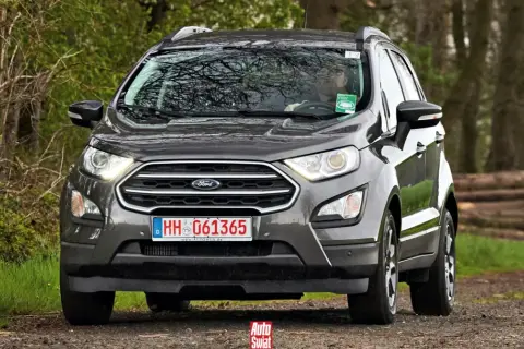 Szary Ford Ecosport na leśnej drodze. Kierowca w okularach za kierownicą.