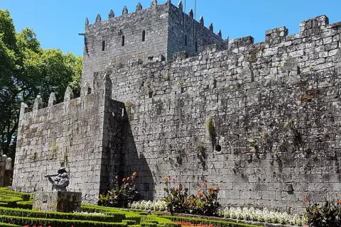 El imponente castillo de Sotomayor se alza sobre un jardín cuidado, con sus muros de piedra y almenas bajo un cielo azul.