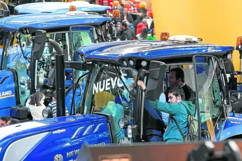 Tractores New Holland en la FIMA Zaragoza 2026. Personas observan los nuevos modelos, algunos niños curiosos se asoman.