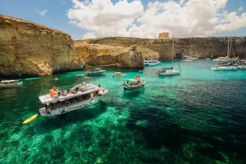 Malta, wrzesień: turkusowa woda, klify i łodzie w Zatoce Błękitnej. Idealna pogoda na rejs.