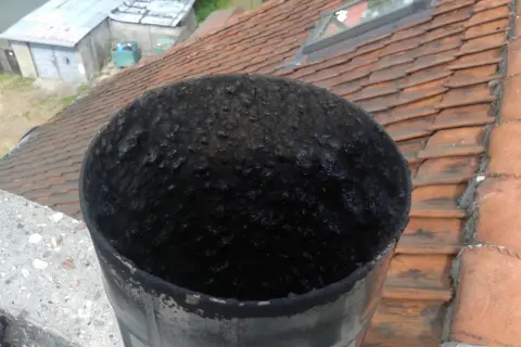 Zatkana sadzą rura kominowa. Zastanawiasz się, ile wytrzymuje wkład kominowy? Ten widok sugeruje, że czyszczenie jest konieczne.