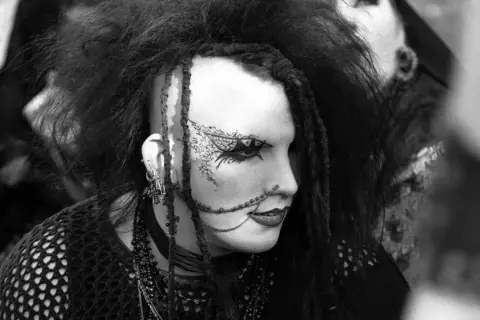 Ein Goth mit auffälligem Make-up und Dreadlocks, inspiriert von der Ästhetik von Goth-Bands.