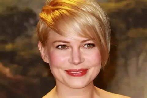 Kobieta z okrągłą twarzą i stylową, krótką fryzurą w odcieniu blondu.