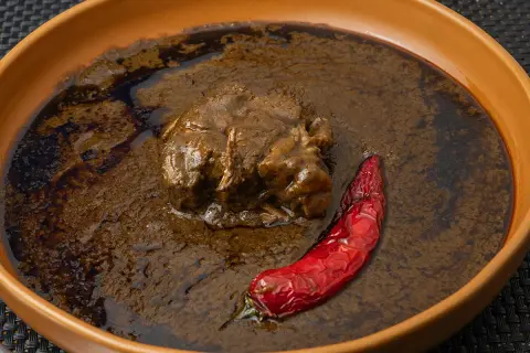 Un plat de mloukhia égyptienne, un ragoût de viande savoureux, servi avec un piment rouge séché dans un bol en terre cuite.