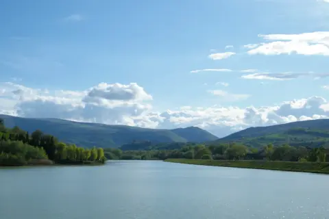 Vasto lago delle grazie con colline verdi e cielo azzurro con nuvole bianche.