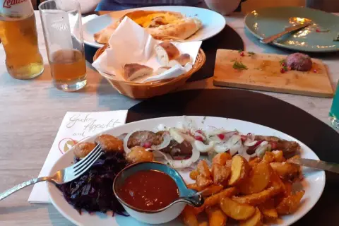 Ein köstliches Gericht mit Fleischspieß, Kartoffelspalten und Rotkohl in einem georgischen Restaurant in Halle.