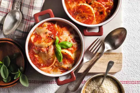 Gnocchi alla Romana ricetta della nonna: dischi dorati al forno, ricoperti di sugo di pomodoro e formaggio filante, guarniti con basilico fresco.
