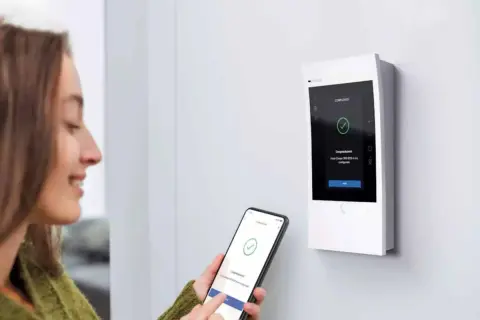 Une femme utilise son smartphone pour configurer un interphone Bticino Classe 300. L'écran affiche "Completato".