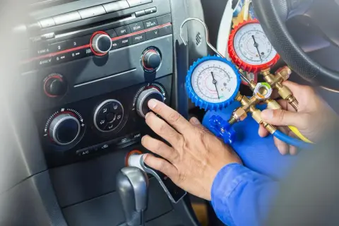 Mechanik sprawdza, ile czynnika do klimatyzacji pozostało w samochodzie, używając manometrów.