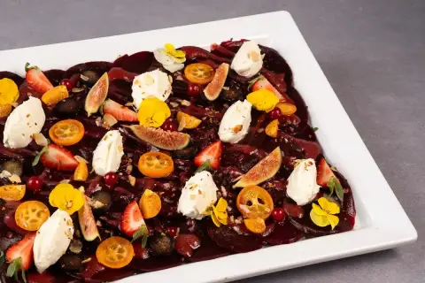Eleganckie carpaccio z buraka z kawałkami fig, truskawek, kumkwatów, serka i jadalnych kwiatów.