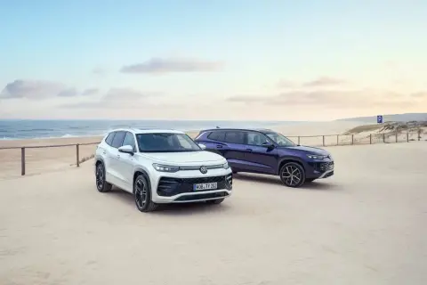 Dwa SUV-y, biały i granatowy, zaparkowane na piaszczystej plaży. To nowe modele VW Tayron, gotowe na przygodę nad morzem.