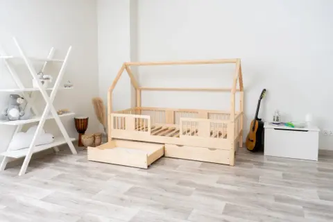 Łóżko domek z litego drewna sosnowego, z szufladami, obok regał, bębny i gitara.