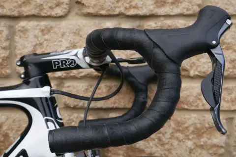 Czarna owijka na kierownicę roweru szosowego z subtelnym wzorem. Widoczna manetka Shimano i mostek PRO.