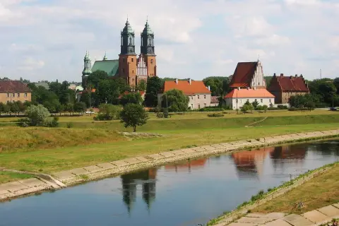 Widok na Ostrów Tumski w Poznaniu z katedrą i innymi zabytkowymi budynkami nad rzeką Wartą.
