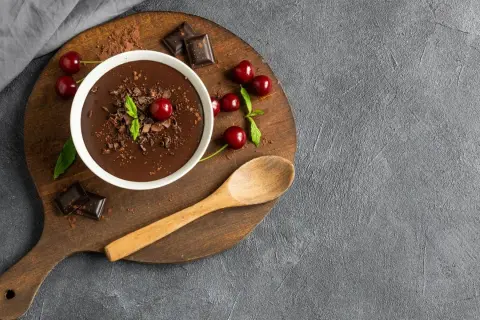 Pyszny budyń czekoladowy z wiśniami i miętą. Zastanawiasz się, ile kcal ma budyń czekoladowy? Ten deser wygląda na bogaty w smak!