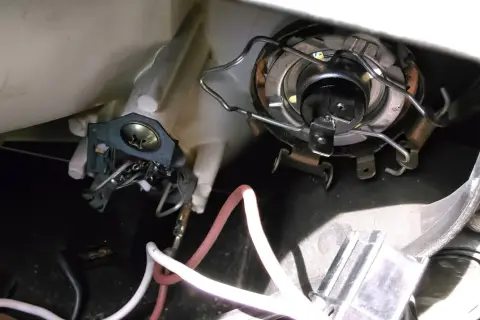 Wymiana żarówki przód Mitsubishi Colt. Widoczny mechanizm mocowania żarówki i przewody.