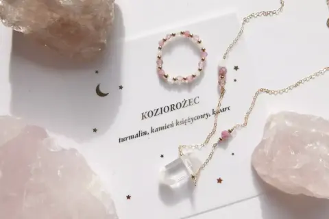 Delikatna biżuteria z różowych kamieni i kryształu, ozdobiona gwiazdkami i księżycem, nawiązuje do znaku zodiaku Koziorożec.