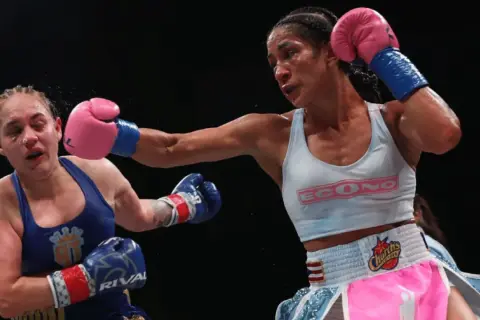 A boxer lands a powerful jab, her opponent reeling from the impact. The intensity of the fight is palpable, showcasing the raw emotion and skill involved in boxing terms.