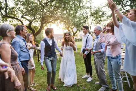 Ein glückliches Brautpaar, schick legere gekleidet, wird von seiner Familie im Garten gefeiert.