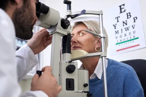 Okulista wykonuje badanie nerwu wzrokowego u pacjentki przy użyciu specjalistycznego sprzętu.