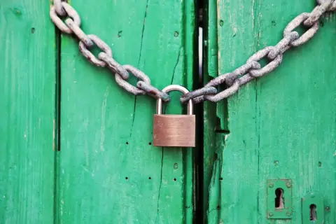 Puerta verde cerrada con cadena y candado. Un símbolo de que se puede quitar el usufructo de una vivienda.