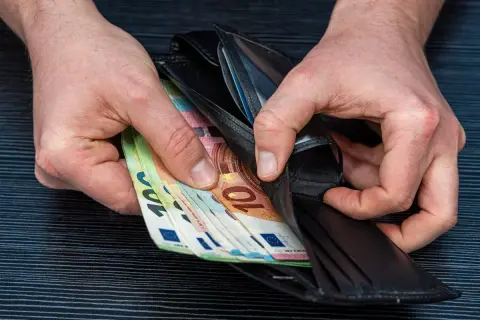 Ręce wkładają do portfela banknoty euro. Zarobione pieniądze po ciężkiej pracy lakiernika.