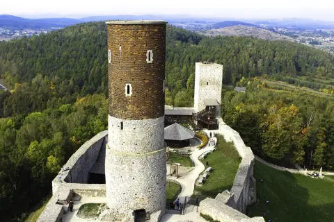 Zamek Krzyżtopór w Górach Świętokrzyskich, z charakterystyczną wieżą i murami obronnymi, otoczony jesiennym lasem.