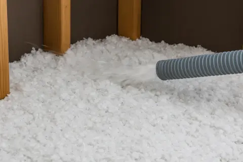 Installazione di isolamento sfuso. Attenzione: la lana di vetro pericolosa può irritare pelle e polmoni.