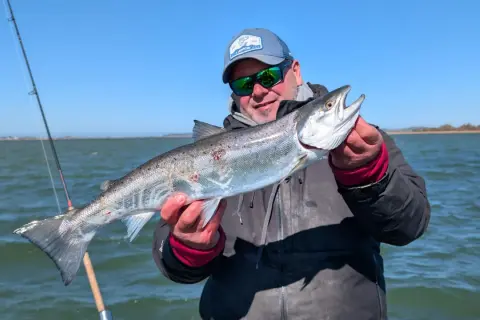 Glücklicher Angler hält stolz einen großen Fisch, den er beim Limburg Angeln gefangen hat.