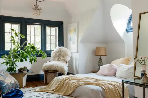 A cozy bedroom with a fluffy chair, plush pillows, and a soft throw blanket. Learn how to create a cozy bedroom with these inviting elements.