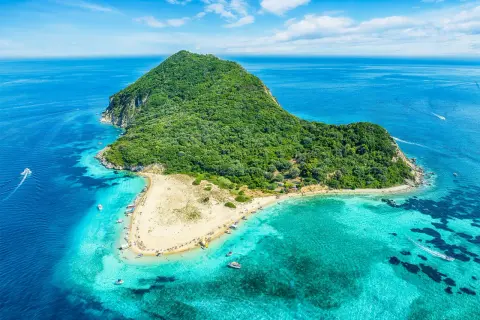 Malownicza wyspa Caretta Island na Zakynthos, z piaszczystą plażą i turkusową wodą, otoczona zielonymi wzgórzami.