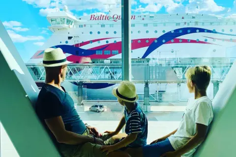 Familjen väntar på sin 40 timmars kryssning. En stor färja, Baltic Queen, ligger vid kajen.