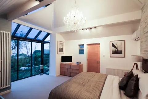 Habitación moderna con grandes ventanales que dan a un jardín. Ideas para como hacer un balcón en una casa ya construida.