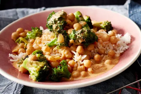 Ein Teller mit Reis, Kichererbsen und Brokkoli in cremiger Sauce. Ein leckeres Gericht, das zeigt, wie vielseitig Kichererbsen-Rezepte sein können.