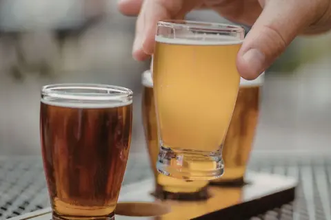 Assaggio di una fresca italian pale ale dorata, con un'altra birra ambrata in primo piano.