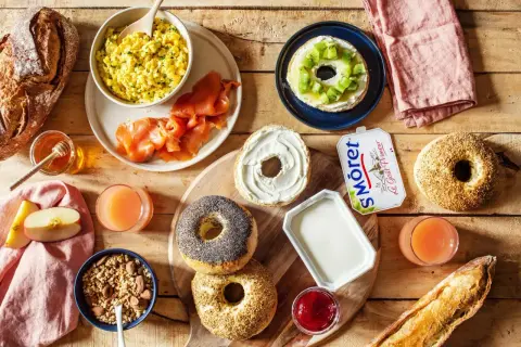 Un petit déjeuner peu calorique avec œufs brouillés, saumon fumé, bagels, fromage frais, fruits et jus.