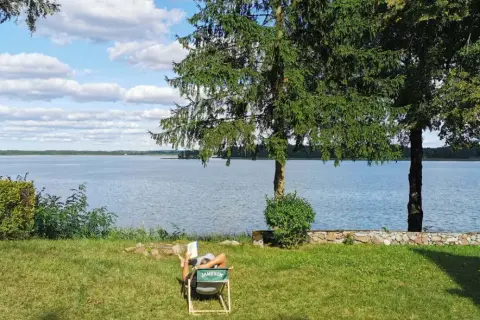 Osoba odpoczywa nad jeziorem, ciesząc się spokojem. To jedno z tych magicznych miejsc Kujawsko-Pomorskiego, gdzie czas płynie wolniej.