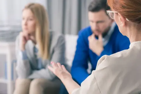 Terapeutka prowadzi interwencję kryzysową z parą. Kobieta i mężczyzna siedzą zamyśleni, szukając wsparcia.
